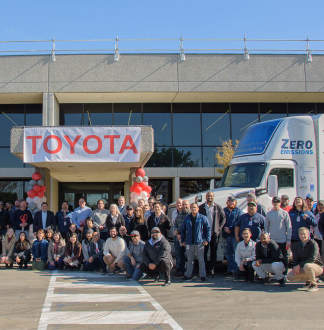 Toyota employees pose for picture in front of office building and zero emissions truck