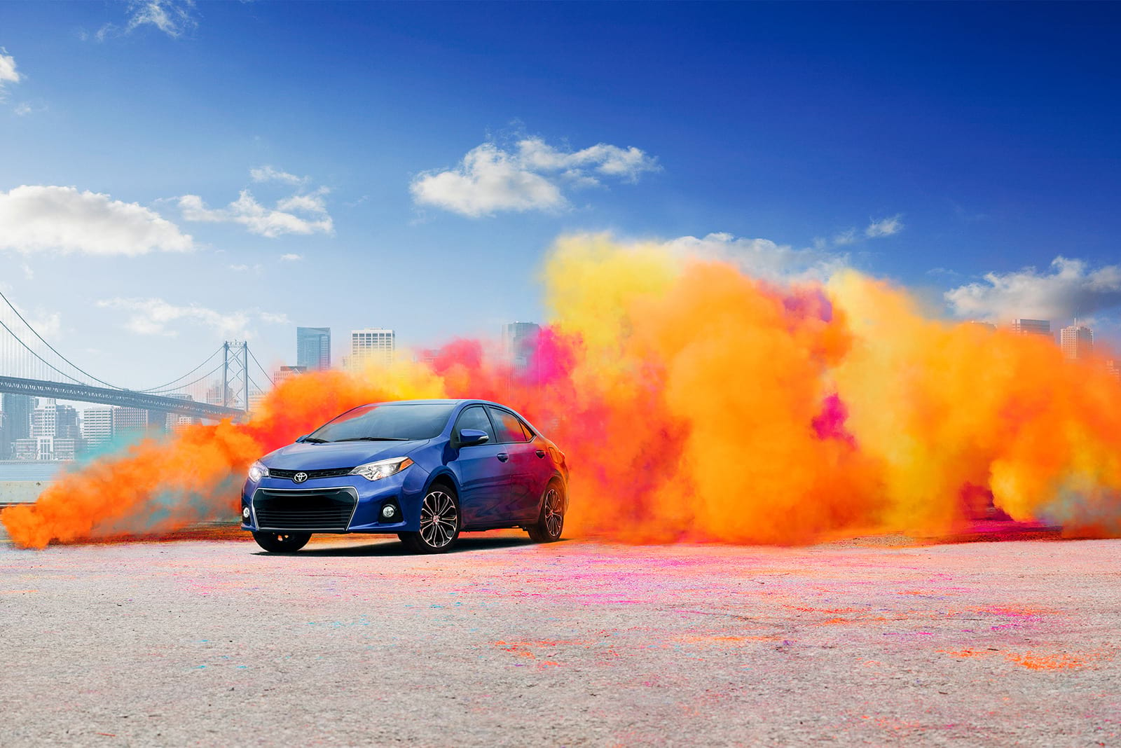 Toyota vehicle with multicolored dust cloud and city skyline