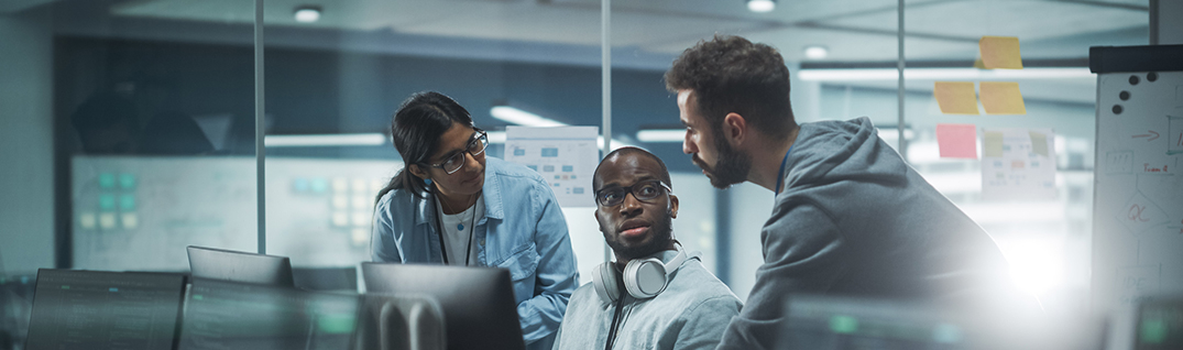 Three ITx Cybersecurity team members meet around workstation