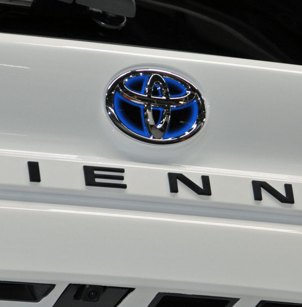 Closeup of the Toyota logo on a white Sienna Hybrid