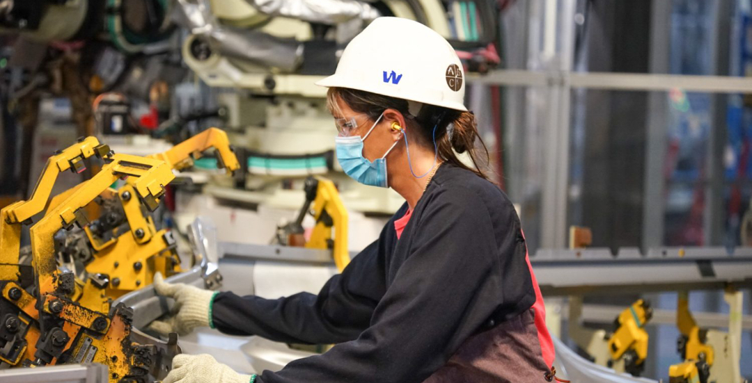 Picture of an emplayee working on machine part,